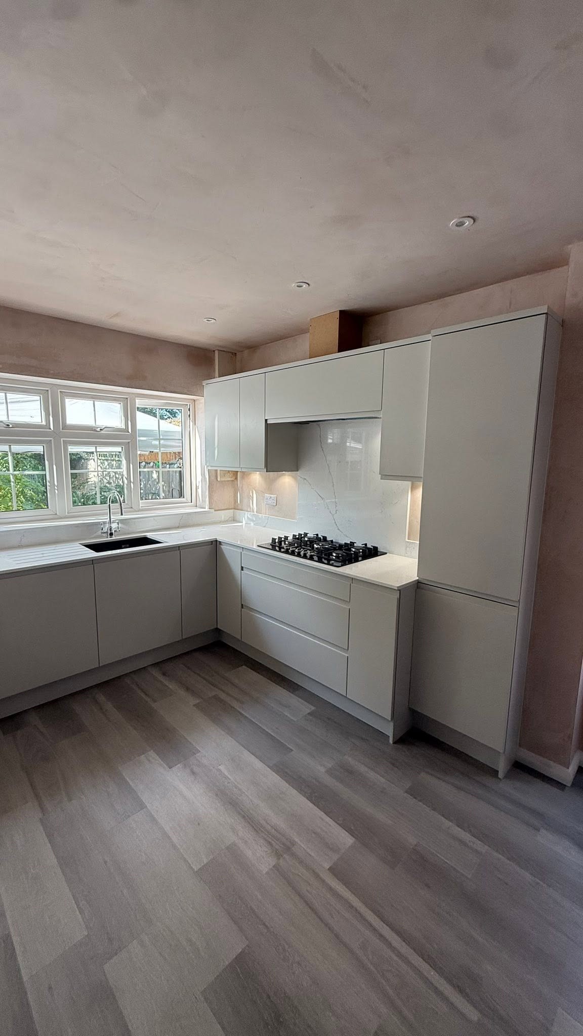 Light grey handleless kitchen with a wood-effect floor, fitted in Kenilworth