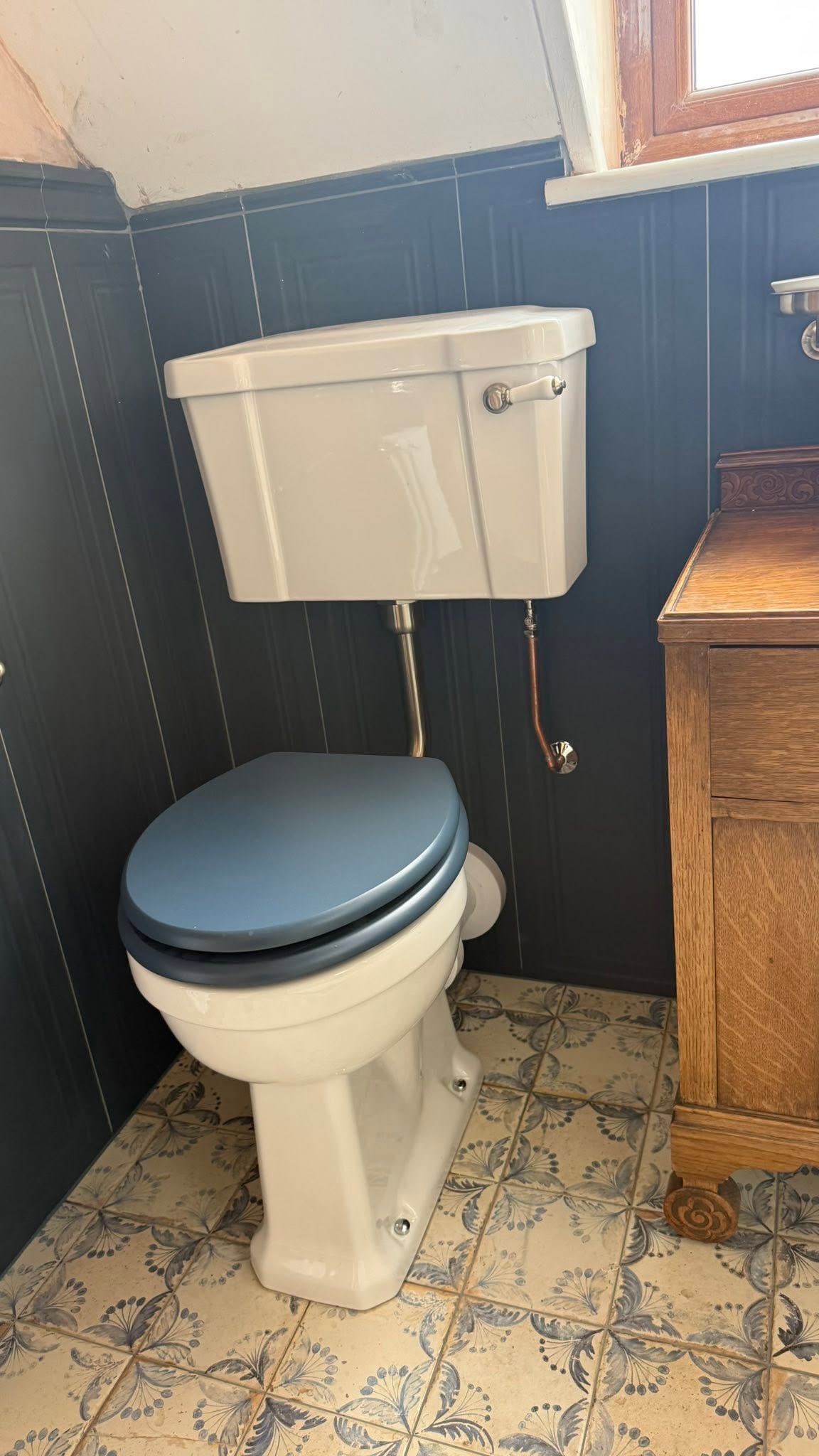 Toilet with a blue seat against navy panelling