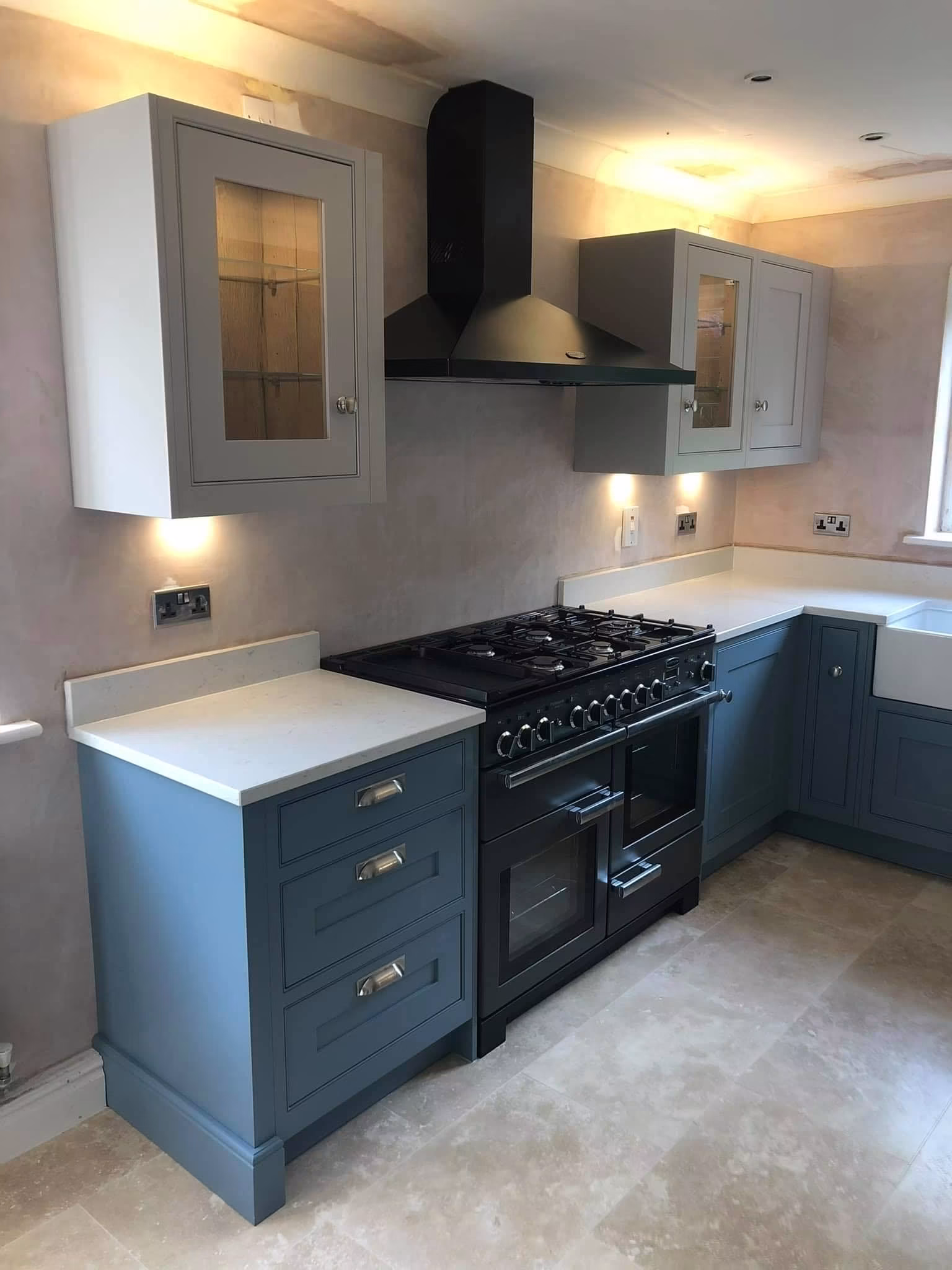 Blue shaker kitchen with a range cooker, black chimney hood, glazed wall units and pale worktops