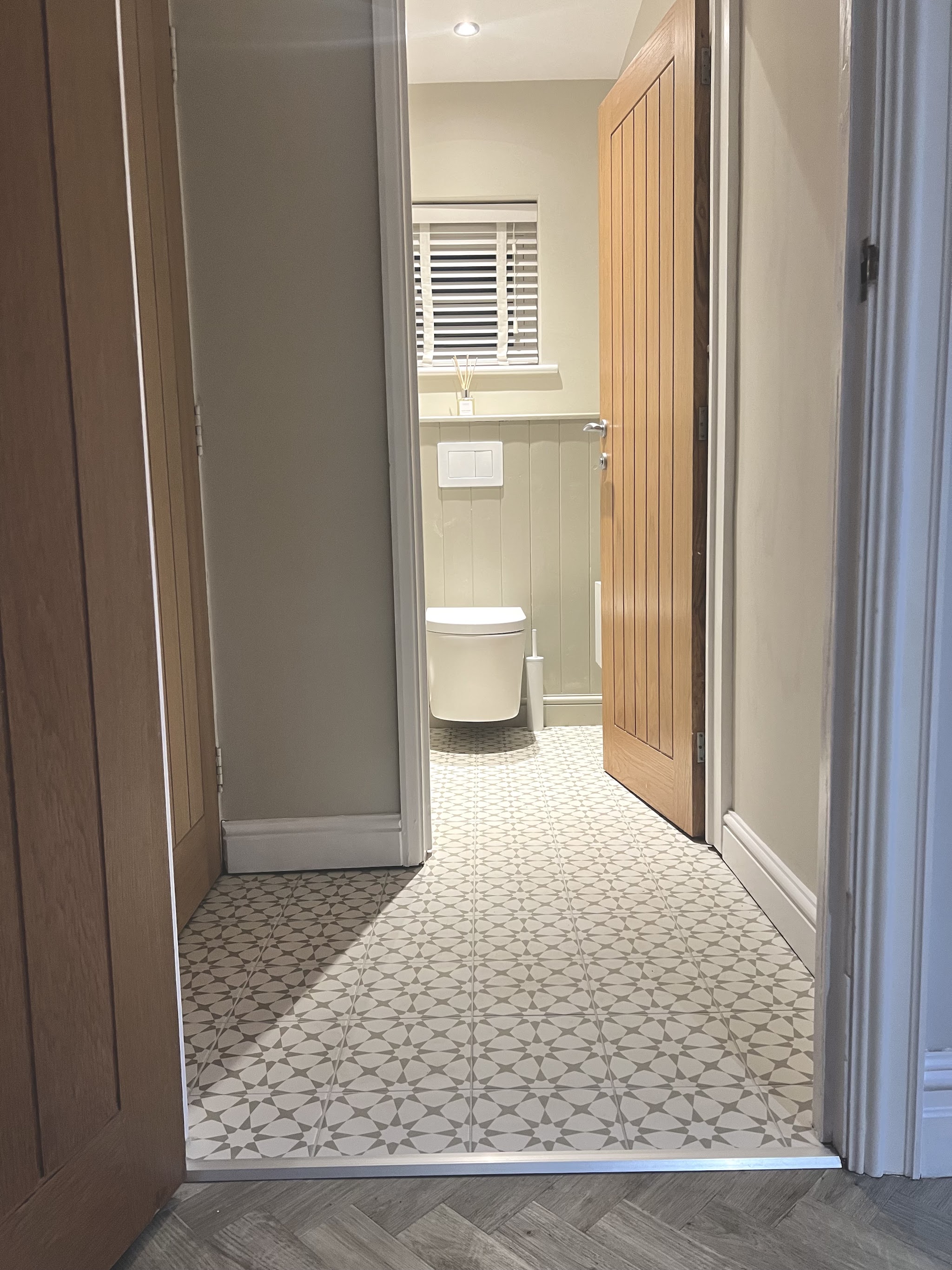 Downstairs cloakroom seen from the hallway, with panelling and patterned floor tiles