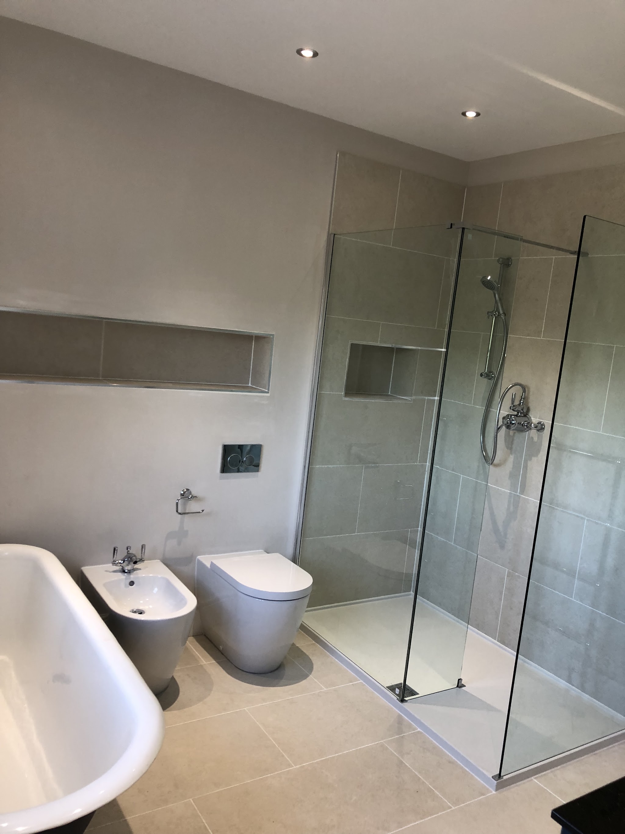Finished bathroom with a freestanding roll-top bath, back-to-wall toilet and bidet, and a walk-in glass shower